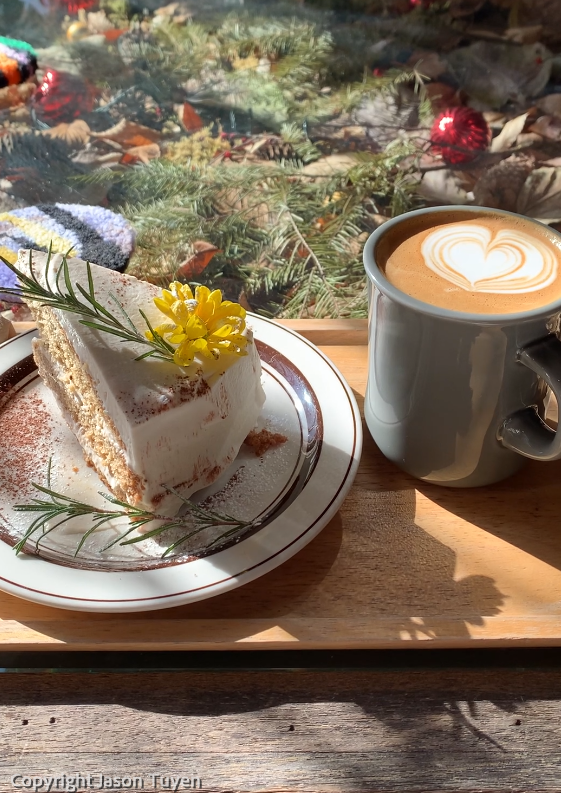 Slice of earl grey cake and hot cup of vanilla latte set on top of a serving tray.